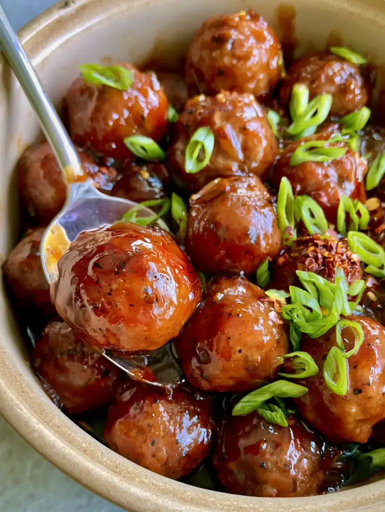 Honey BBQ Crockpot Meatballs: The Ultimate Sticky Mahogany Glaze Recipe 2 Close-up of mahogany-red honey BBQ Crockpot meatballs with visible black pepper specks and fresh scallions.