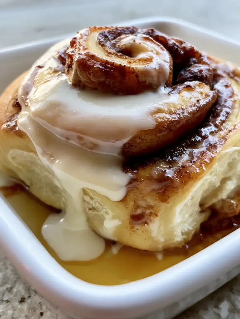 Cinnamon Rolls Recipe: The Secret to Giant Pillowy Rolls with a Heavy Cream Soak 1 Velvety cream cheese frosting cascading down the spiraled layers of a fresh cinnamon roll. (cinnamon rolls recipe)