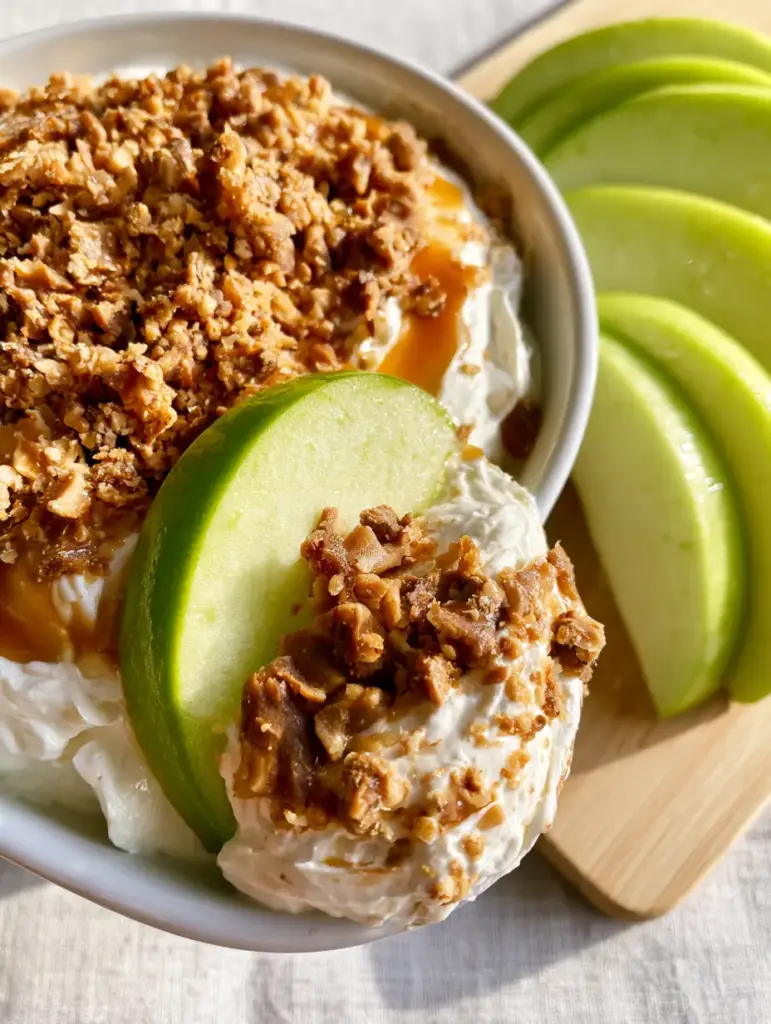 Overhead view of Apple toffee dip with a green apple slice scooping the caramel-drizzled dip.